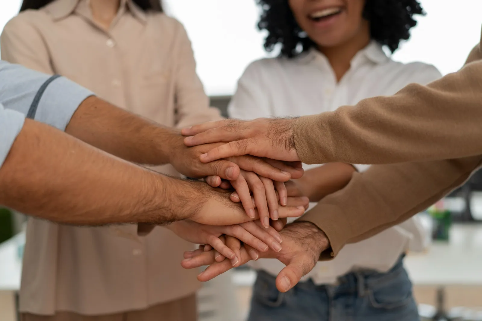 Equipa unida com as mãos sobrepostas, símbolo de ligação e confiança